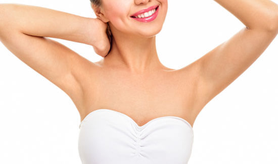 Picture of a woman holding her arms up and happy with her perfect arms liposuction procedure she had with Costa Rica MedVentures in beautiful San José, Costa Rica.  The woman is wearing a white top and smiling to the camera.