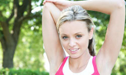 Picture of a woman, happy with her arms liposuction procedure she had with Top Plastic Surgeons in beautiful San José, Costa Rica.  The woman is facing the camera with arms outstretched with a backdrop of green trees.