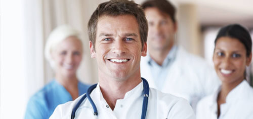 Picture of a group of doctors representing the quality care you will receive with the Top Plastic Surgeons in Costa Rica. The picture shows a doctor in a white shirt with a stethoscope around his neck, and 3 associates standing behind him.