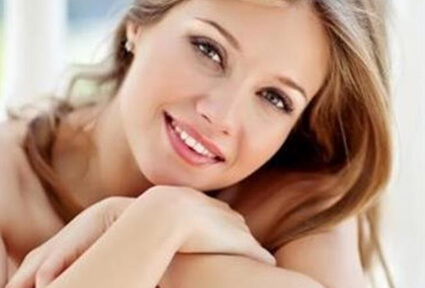 Picture of a trim woman sitting with arms crossed, and happy with her perfect Labiaplasty she had with top plastic surgeons in beautiful San José, Costa Rica.  The woman has long sandy blonde hair and is facing the camera with head slightly tilted.