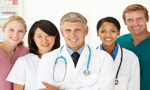 Picture of a smiling medical team representing doctors in beautiful San José, Costa Rica.  The picture shows five members of the medical group standing together, facing the camera, and smiling.